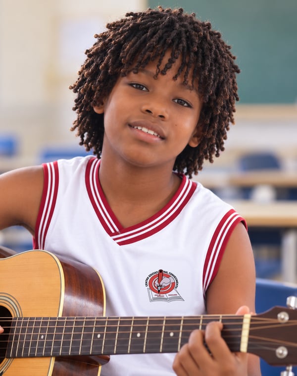 Aluno do CEC tocando violão na aula de Musicalização