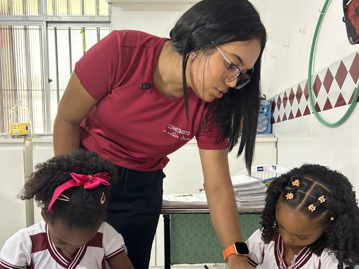 Professora do CEC orientando duas alunas na atividade do caderno