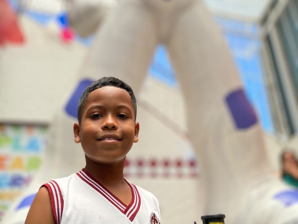 Aluno do CEC sorrindo em frente ao astronauta gigante no passeio ao planetário